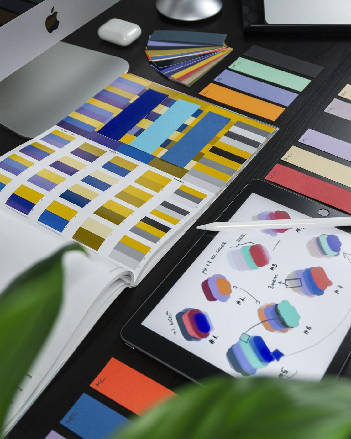 Colour swatch books and palette studies on a dark desk